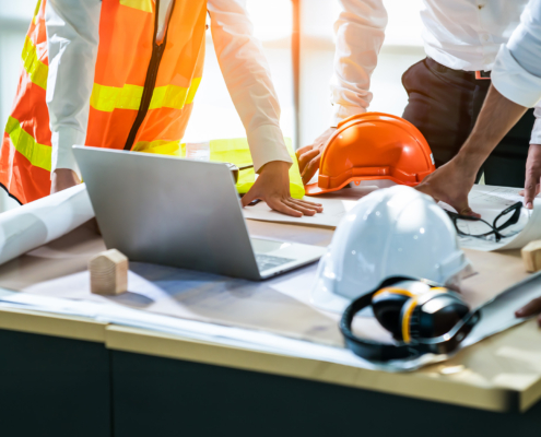 Side view of construction workers surrounding design blueprints